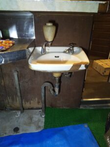 板橋区板橋で交換前のTOTO製手洗い器を確認した様子