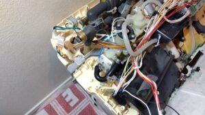 江東区豊洲の一体形トイレ機能部でTCH785N交換前のホースと配線を確認している状態