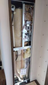 春日部市南で電気温水器の前面カバーを外し内部の配管と電気接続部を確認している状態