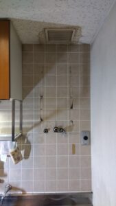 既存の電気温水器を撤去し、タイル壁の配管接続口と固定部分が見える状態