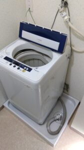 新しい洗濯機パンに既存の洗濯機を戻し排水ホースを接続した状態